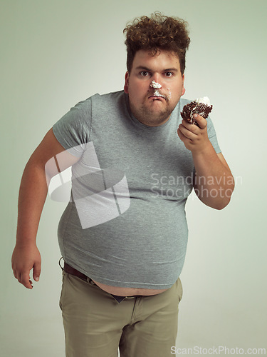 Image of Plus size, eating and portrait of man with cake in studio for unhealthy, sugar and sweet snack. Greedy, food and male person with messy slice of chocolate dessert isolated by gray background.