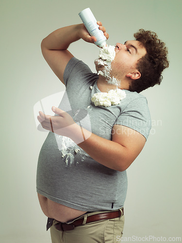 Image of Sweet, dessert and man with whipped cream for eating in studio background, addiction and unhealthy for plus size male person. Guy, health problem and risk for diabetes with sugar and cholesterol