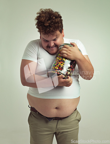 Image of Candy, jar and crazy plus size man in studio for snacks, sweets and dessert in container. Comic, funny and isolated silly person with glass for unhealthy diet, sugar and treats on white background