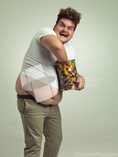 Image of Sweets, crazy and portrait of man in studio for luxury snacks, sugar and dessert in jar. Comic, funny facial expression and plus size person with glass container for unhealthy diet on background