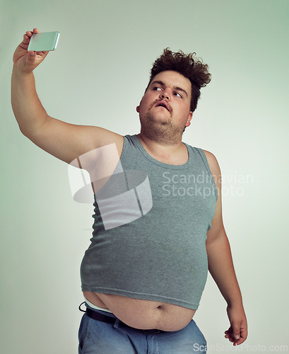 Image of Selfie, fashion and plus size man in studio posing with casual, trendy and cool outfit with stomach. Style, serious and crazy male person with photography picture isolated by gray background.