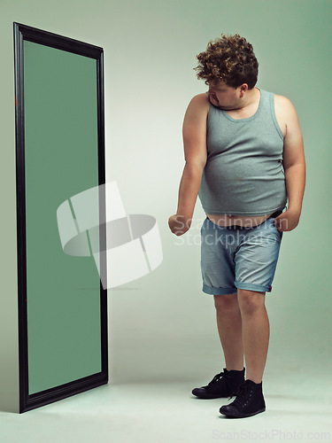 Image of Man, flex and body image in mirror for eating disorder, anxiety and mental health. Depression, weight gain and insecurity for plus size male person, reflection and muscle and frustrated or sad