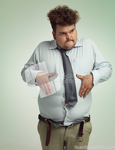 Image of Man, stomach and plus size with belly from unhealthy diet or weight gain on a studio background. Young male person or big guy holding tummy for eating disorder or body conscious on mockup space