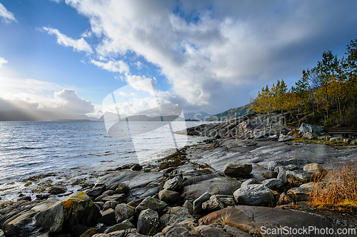 Image of Majestic coastal scenery with sunlit rocks and dramatic sky at d