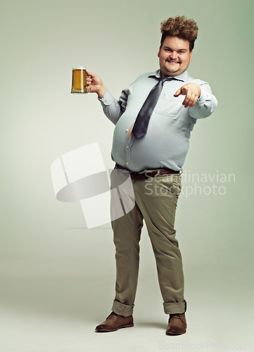 Image of Man, portrait and pointing to you with beer for celebration, drink or party on a studio background. Male person or plus size model with glass or mug for beverage, wine or drinking on mockup space