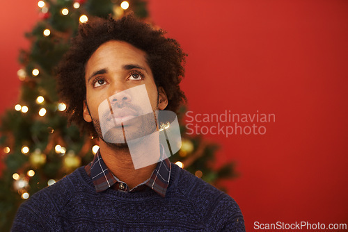 Image of Man, thinking and Christmas holiday at tree for festive season thoughts for present, vacation or celebration. Male person, contemplating and red background with mockup space, decoration or lights