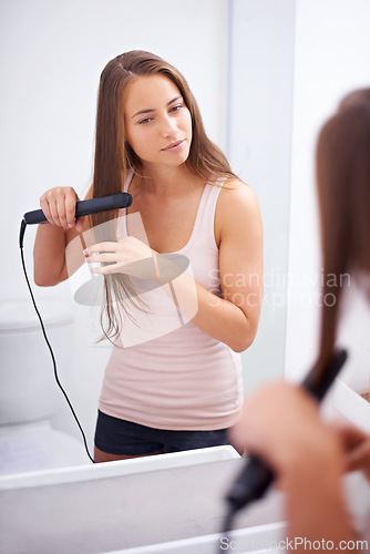 Image of Girl, smile and bathroom to iron hair with straighter in house, care and style with tool. Happiness, woman and female person with electric flat with heat for adult with reflection on mirror in home