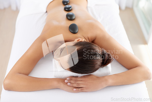 Image of Hot stone, salon and massage table for closeup, luxury and wellness with skin, spa and oil. Woman, self care and natural heat therapy for stress relief, zen and care with body, beauty and wellbeing