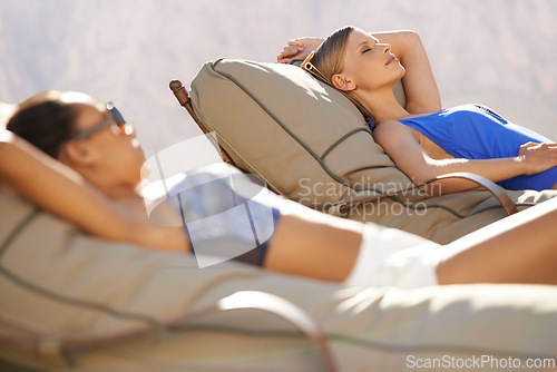 Image of Women, swimwear and lounge chairs for poolside, relax or tanning during summer vacation in Australia. Diverse, female tourists and lying down at holiday resort, wellness spa and luxury hotel