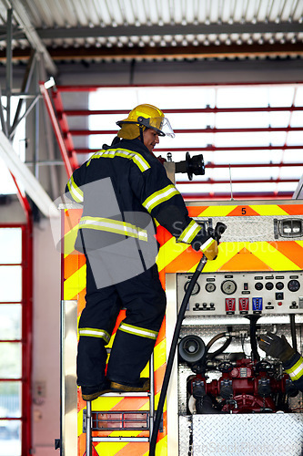 Image of Firefighter, ladder and safety worker with hose truck at a fire station with emergency service employee. Uniform, firetruck and helmet of a fireman ready for rescue working with equipment at a job