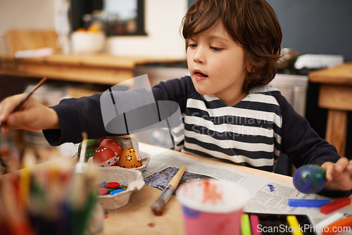 Image of Happy child, creative and color painting of eggs and celebration of easter holiday in home. Young, artist and boy with inspiration for learning craft, mural and paintbrush with supplies in kitchen