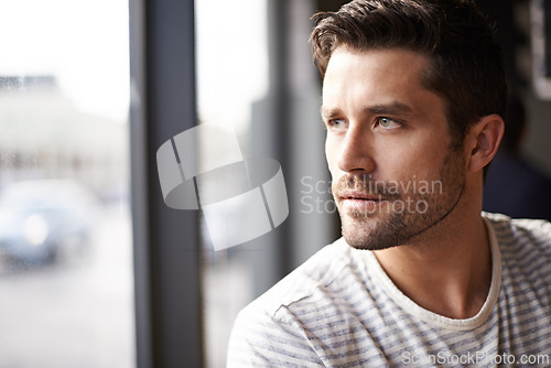 Image of Handsome man, thinking and vision by window at cafe for ambition, travel or sightseeing. Face of male person waiting in wonder or thought at indoor restaurant or coffee shop for break or reflection