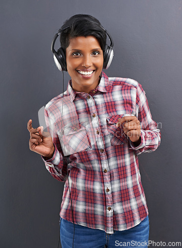 Image of Happy woman, portrait and dancing with headphones for music or podcast on a gray studio background. Young female person or Indian with smile enjoying or listening to audio or sound track with headset