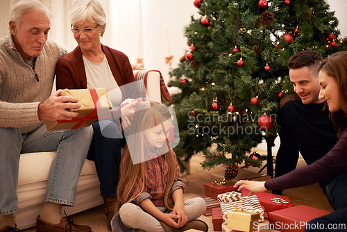 Image of Family, christmas tree and gifts with kids, parents and grandparents together with giving in living room. Home, happy and present with holiday and celebration at a party with love, care and bonding