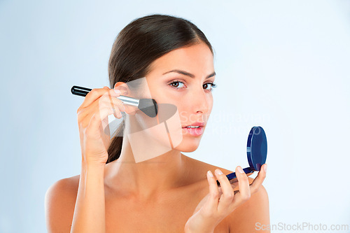 Image of Portrait, woman and makeup with brush and compact for foundation or blush with beauty on blue background. Powder, cosmetics and product for cosmetology with tools, skin glow and facial in studio