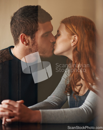 Image of Happy couple, kiss and love with affection for support, intimacy or romance together at indoor cafe. Man and woman holding hands and touching for date, relationship or romantic bonding at coffee shop