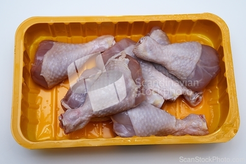 Image of raw chicken legs in a plastic container on a white