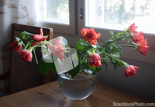 Image of roses in a glass vase on a wooden table