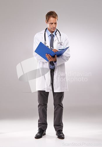 Image of Clipboard, doctor and man in studio writing notes for medical research, insurance and report for hospital. Healthcare, clinic and worker with documents for consulting and planning on gray background