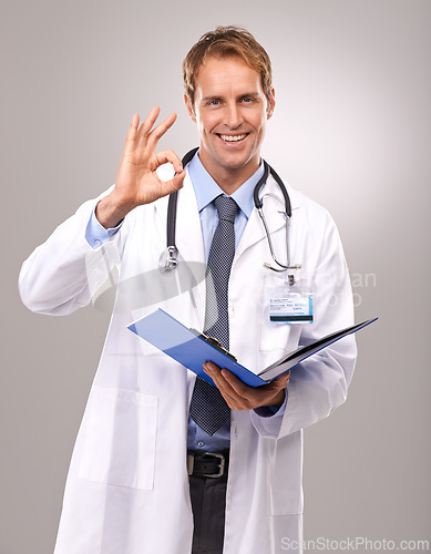 Image of Clipboard, okay sign and portrait of doctor in studio for medical review, documents and report. Healthcare, hospital and man with hand gesture for success, good news and consulting on gray background