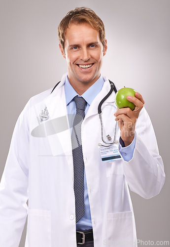 Image of Man, doctor and apple in studio portrait, medical expert and dietician on gray background. Happy male person, fruit and proud of choice or decision for nutrition, vitamins and minerals for health