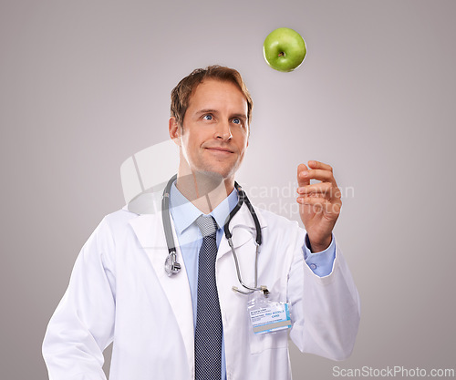 Image of Man, doctor and apple for healthcare in studio, medical expert and dietician on gray background. Male person, fruit and proud of choice or decision for nutrition, vitamins and minerals for health