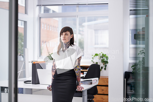 Image of Tattoos, thinking and business woman in office with planning, brainstorming or ideas face. Grunge, reflection and professional edgy female creative designer with ink skin standing in modern workplace