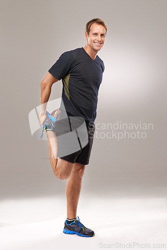 Image of Portrait, man or stretching as flexibility, mobility or exercise for wellness, workout or training. Happy, runner or athletic male person as strong, proud or muscle care in studio on grey background