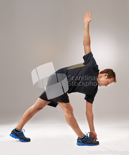 Image of Man, fitness or training with stretching, mobility or workout as exercise, self care or strength. Runner, athletic person or sportsman in muscle, flexibility or warm-up in studio on grey background