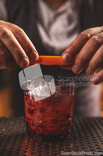 Image of Bartender twisting orange peel over a craft cocktail