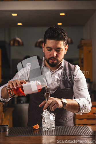 Image of Professional bartender crafting cocktail at bar