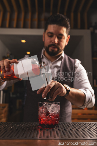 Image of Professional bartender pouring a cocktail at bar