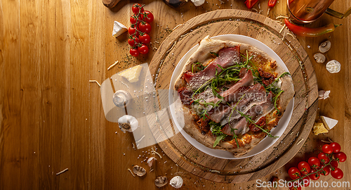 Image of Rustic Italian pizza with arugula and prosciutto