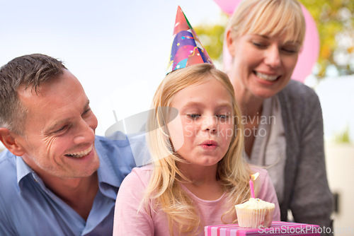 Image of Girl, blowing or candle at happy birthday, party or cake as fun wish, family or bonding together. Papa, mama or child or smile at celebration, congratulations or childhood growth and development