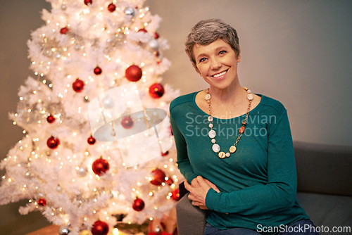 Image of Christmas, tree and portrait of mature woman in home for holiday, festival or celebration on vacation. Happy, person and relax on sofa with festive xmas decoration in living room and enjoy retirement