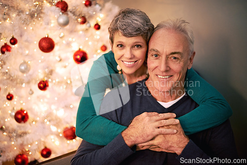 Image of Christmas, portrait and senior couple hug with love, care and support together in a home on holiday. Tree, retirement and marriage with a smile and happy in a house with celebration and santa hat