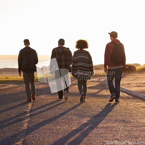 Image of Walking, sunset and back of friends on vacation, travel or holiday together with skateboard. Summer, evening and group of young people by outdoor ocean or sea on weekend trip for bonding in nature.