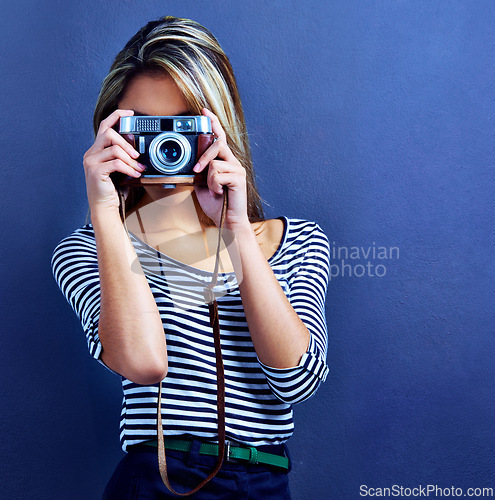 Image of Woman, photographer and camera by face in studio for creativity, media and journalist job by blue background. Girl, retro lens and photography with photoshoot for magazine, collection and newspaper