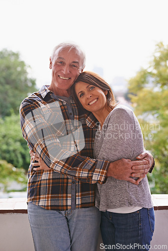 Image of Senior couple, happy and portrait on balcony with hug, love and outdoor with connection for retirement. Woman, elderly man and embrace on patio with pride, care and smile at apartment in Germany