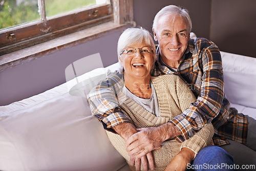 Image of Senior couple, hug and portrait on couch with smile, love and connection in living room for retirement. Elderly woman, old man and embrace on sofa in lounge with pride, care and happy in apartment