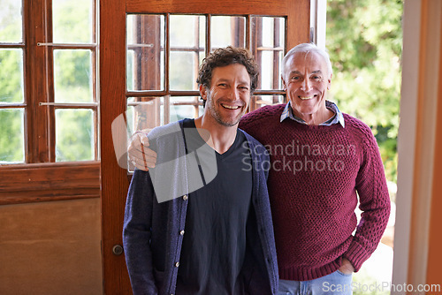 Image of Son, elderly father and portrait in home by front door with hug, smile and bonding with connection. Men, senior dad and adult child with embrace for love, visit and holiday with pride in family house