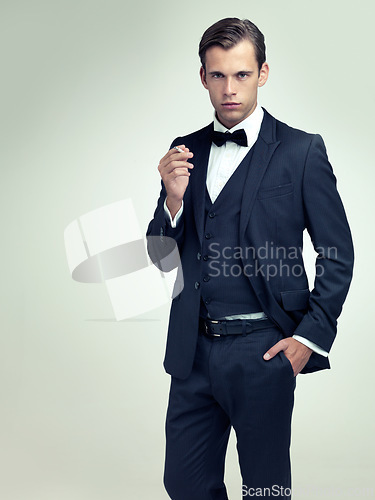 Image of Portrait, serious or young gentleman smoke a cigarette in studio, confidence or vintage fashion by white background. Face, tobacco or man in retro suit or tuxedo, bowtie or hands in pocket for class