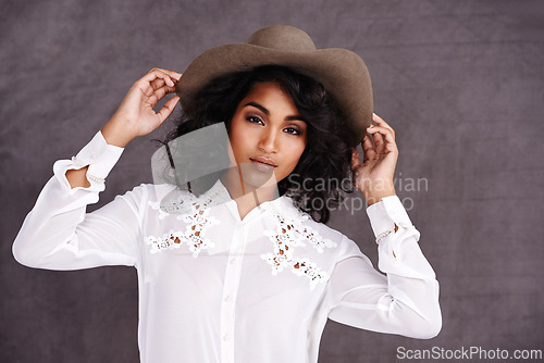 Image of Portrait, studio and woman with cowboy fashion, confidence and relax with girl in stetson hat. Rodeo, western style and face Mexican model with cowgirl culture, wild west clothes and grey background