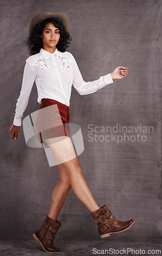 Image of Portrait, studio and woman with western fashion, confidence and relax with girl in stetson hat. Rodeo, cowboy style and face Mexican model with cowgirl culture, wild west clothes and grey background