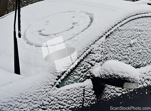 Image of A snow covered car with a smiley face on it