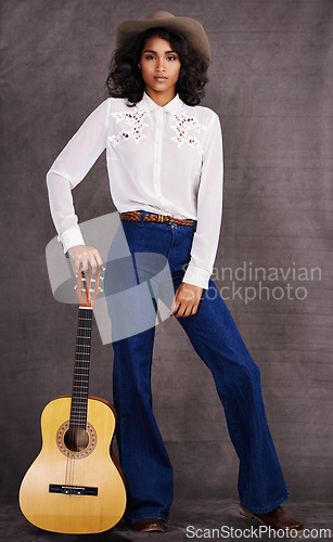 Image of Woman, fashion and musician cowgirl in studio, western clothing and guitar with confidence. Native American, female person in serious portrait for trendy countryside culture, isolated on background