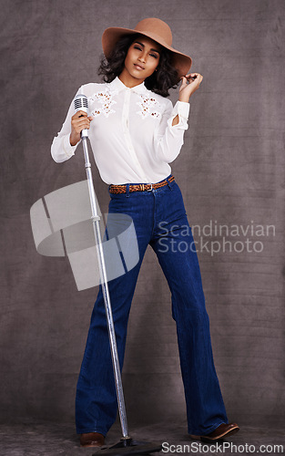 Image of Woman, fashion and cowgirl in studio, microphone and western clothes on proud and confident singer. Musician, female person with trendy hat accessory for countryside culture, isolated on background