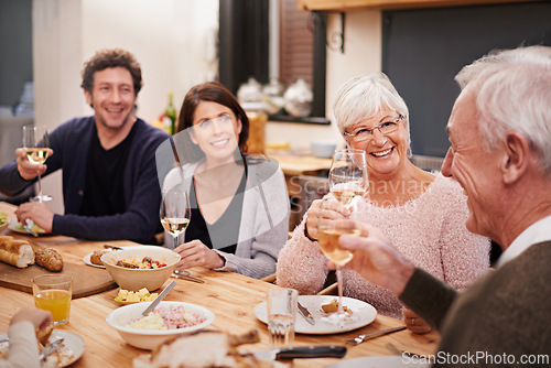Image of Smile, cheers and family at dinner in dining room for party, celebration or event at modern home. Happy, bonding and group of people enjoying meal, supper or lunch together with wine at house.
