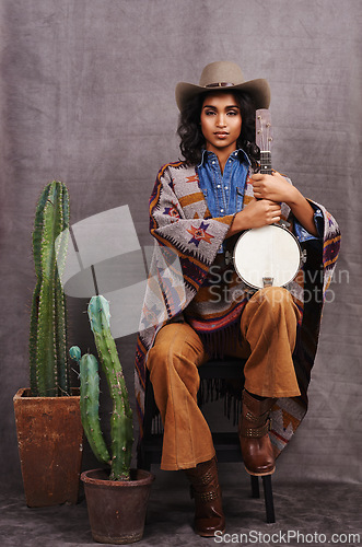 Image of Portrait, cowgirl or woman with instrument for music in studio and cool fashion or clothing on grey background. Native American person, western and model with plants, boho style and banjo for a song