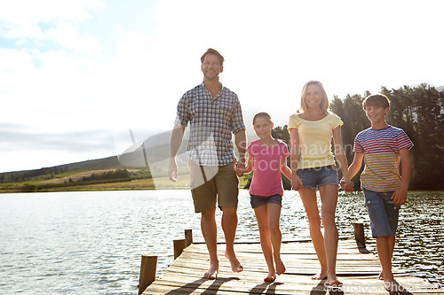 Image of Family, children and pier by lake for holding hands in portrait, happy or vacation with love in summer sunshine. Mom, dad and kids with smile, care or bonding on walk by river for holiday in Colorado